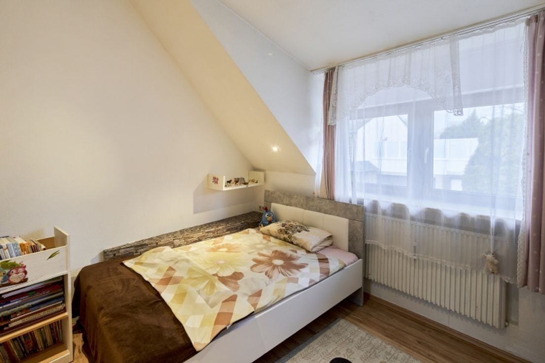 Vorher - Kinderzimmer mit Dachschräge, Bett und Bücherregal vor der Bearbeitung