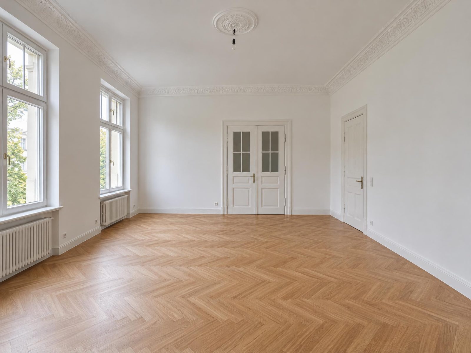 Vorher: derselbe leere Raum mit Blick gerade auf die Flügeltür, Fenster links